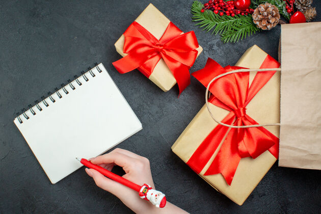 冷杉上图是圣诞气氛与美丽的礼物和冷杉枝针叶树锥旁边的笔记本与笔在黑暗的背景树枝轮子圣诞节