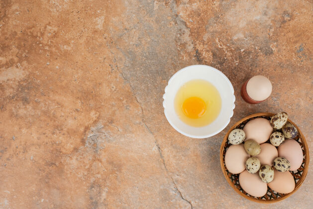 小在大理石表面的白色盘子上放几个鸡蛋和生鸡蛋木头篮子美味