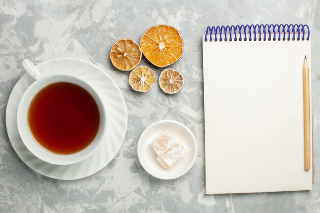 茶顶视图一杯茶 带记事本 放在浅色的桌子上马克杯食品托盘
