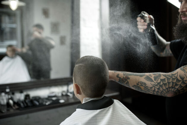 职业儿童理发师在黑暗中剪小男孩服务理发师理发店
