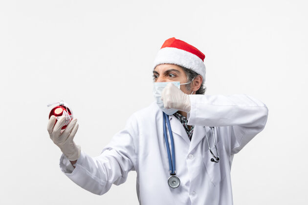 圣诞节正面图男医生手持新年树玩具健康冠状病毒男医生工作制服
