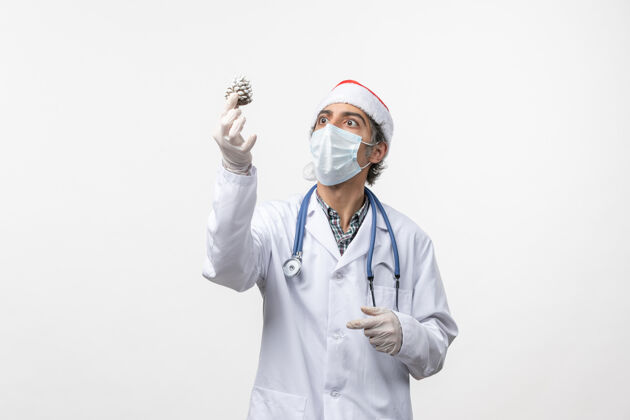 医药正面图：男医生拿着新年树玩具上了白墙病毒健康冠状病毒-圣诞节外套听诊器