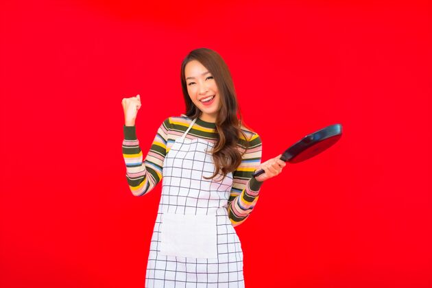年轻画像美丽的亚洲年轻女子拿着锅准备在红墙上做饭健康立场中国