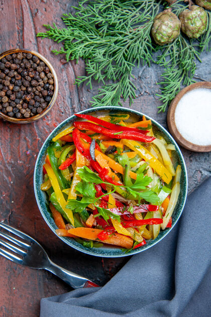 食物顶视图蔬菜沙拉碗群青蓝色披肩黑胡椒叉在暗红色的桌子上蔬菜沙拉胡椒粉午餐