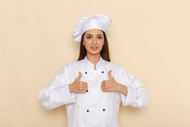 服装身着白色厨师服的年轻女厨师的正面图 在浅白的墙上微笑着 像招牌一样示人展示女工人
