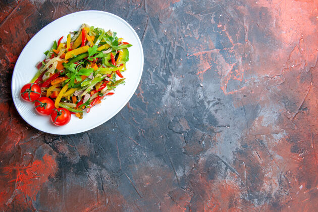 辣俯瞰蔬菜沙拉在椭圆形盘子上的深色桌子上复制的地方辣椒蔬菜菜肴