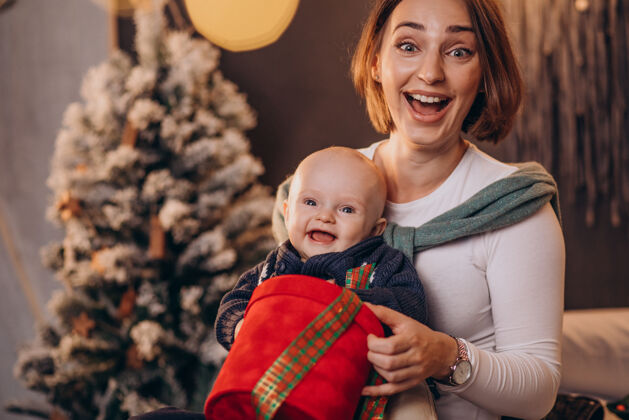 圣诞树妈妈带着她的男婴庆祝圣诞节装饰女人肖像