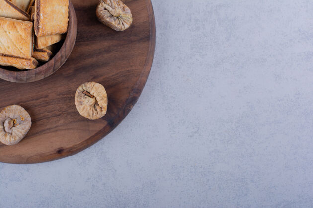 烤的一碗可口的脆饼干和干无花果放在木板上水果干的饼干