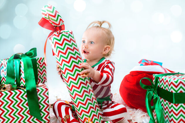 年轻可爱的女婴1岁左右的圣诞老人帽子摆姿势惊讶礼物球