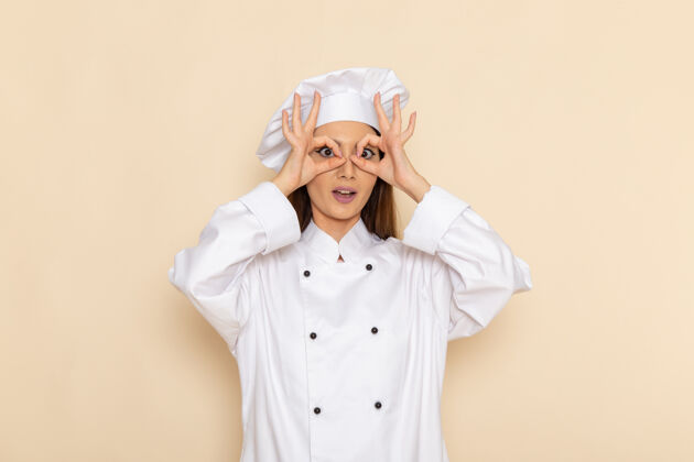 人浅白色墙壁上穿着白色厨师服的年轻女厨师的正视图淋浴帽西装男人