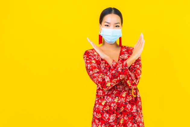 流感肖像美丽的亚洲年轻女子戴上防冠状病毒或冠状病毒的面具在黄色的墙上传播疾病病毒
