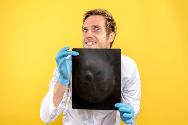 医疗正面图黄色桌子上拿着x光片的男医生医疗外科卫生科维德成人X光Covid