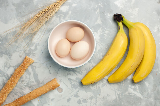 健康顶视图浅白色桌子上的生鸡蛋和面包黄香蕉光可食用水果鸡蛋
