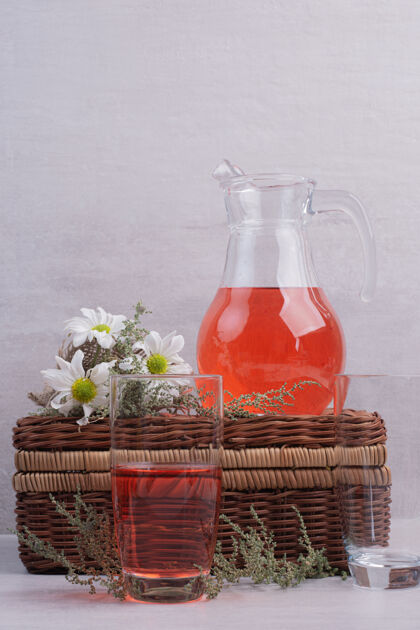 玻璃杯白桌子上放着新鲜的柠檬水和带雏菊的罐子罐子柠檬水点心