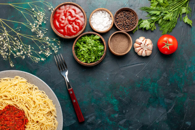 面食顶视图煮熟的意大利面食与肉和不同的调味品在深蓝色的表面食物意大利烹饪