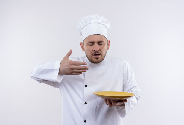 盘子年轻帅气的厨师穿着厨师制服 拿着盘子 举起手 闭着眼睛 在空白处嗅着厨师拿着手