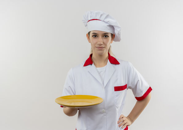 年轻年轻漂亮的厨师穿着厨师制服 手里拿着空盘子 把手放在腰上 在空白处与世隔绝高兴空间漂亮