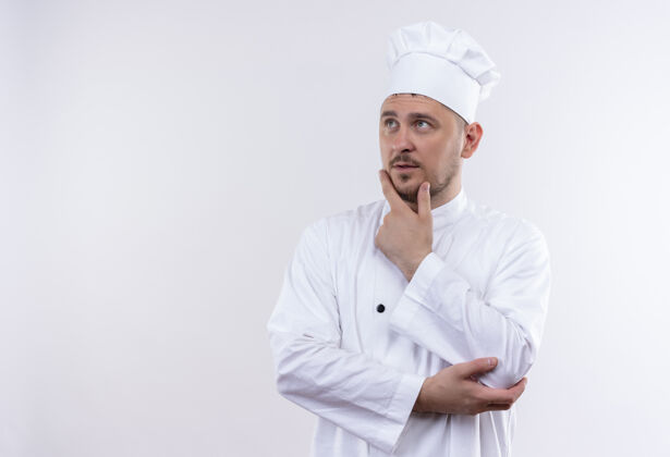 制服体贴的年轻帅哥厨师穿着厨师制服 手放在下巴上 看着旁边的空白处手壁板厨师