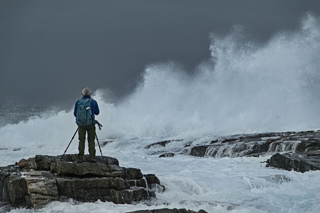 风暴摄影师在暴风海上的岩石上大海岩石季节