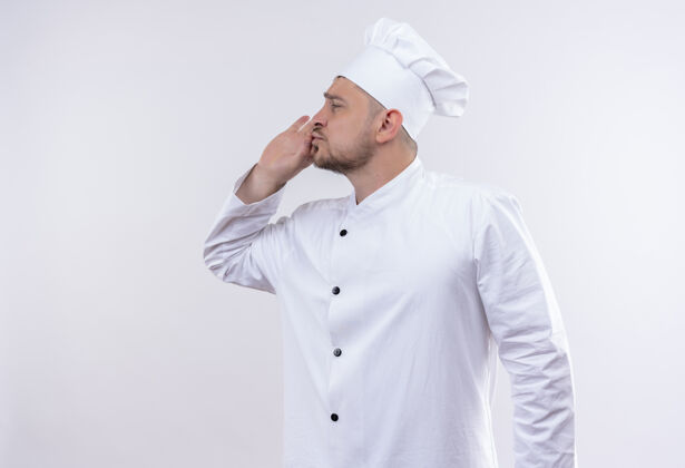 手势年轻帅气的厨师穿着厨师制服 做着可口的手势 看着旁边孤立的白色空间年轻帅气长相