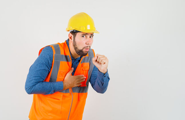 车间年轻的建筑工人在衬衫 背心 头盔咳嗽 看起来不舒服前视图项目安全工匠