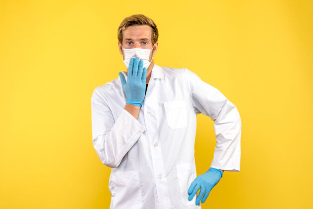 成人正面图男医生戴着无菌口罩上黄色背景健康的冠状病毒大流行男性医生Covid医生