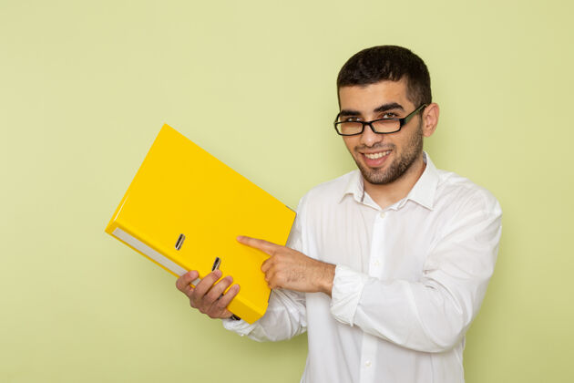 工人身穿白衬衫的男上班族正拿着黄色文件站在浅绿色的墙上人持有人