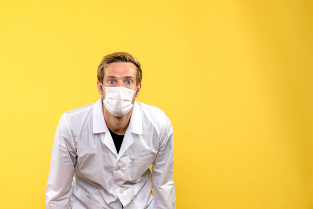 病毒正面图黄色背景上戴着口罩的男医生大流行冠状病毒-健康病毒男性成人男性医生