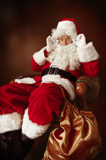 介绍一个穿着圣诞老人服装 留着奢华的白胡子 戴着圣诞老人的帽子 穿着红色服装的男人的肖像夏娃手臂表演
