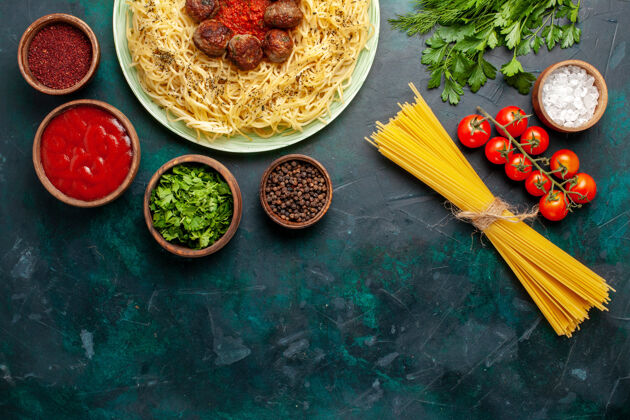 食物俯瞰美味的意大利面食与肉丸和不同的调味品在深蓝色的背景胡椒粉面团一餐