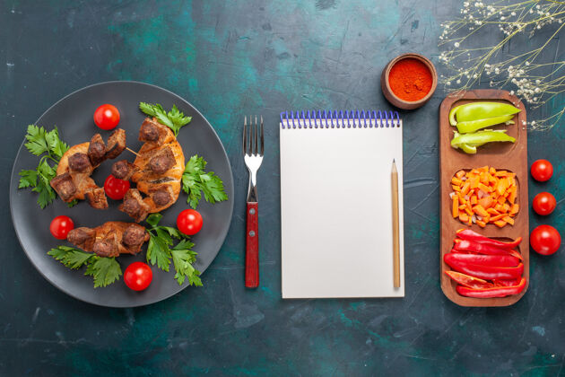 蔬菜俯视图：蓝色背景的盘子里放着蔬菜和樱桃西红柿的肉片胡椒西红柿晚餐