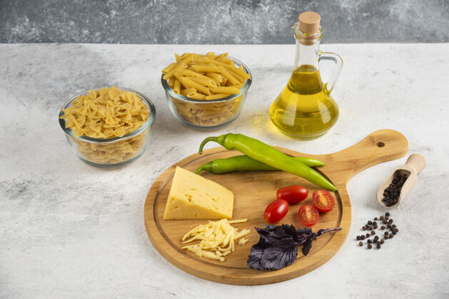 油生面食 油 奶酪和新鲜蔬菜放在大理石上生的西红柿谷物