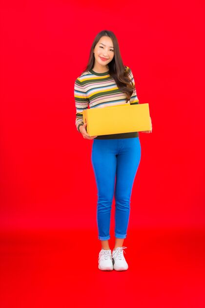 运输在红色的隔离墙上画一幅美丽的亚洲年轻女子拿着包裹盒满意航运包裹