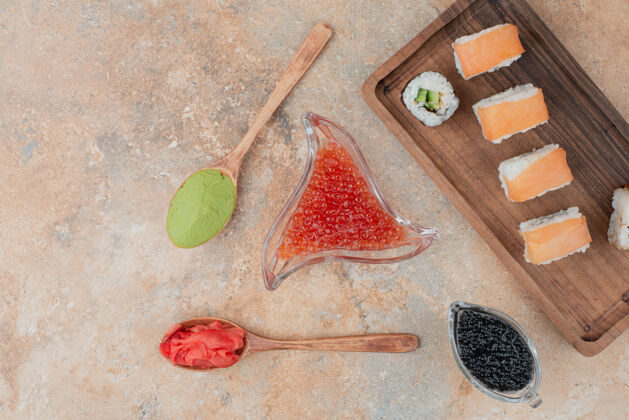 米饭美味的寿司 鱼子酱 姜和瓦萨比放在木盘上食物顶部顶部观点