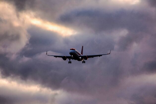 旅行一架飞机从乌云密布的天空降落的低角度镜头运输电力地平线
