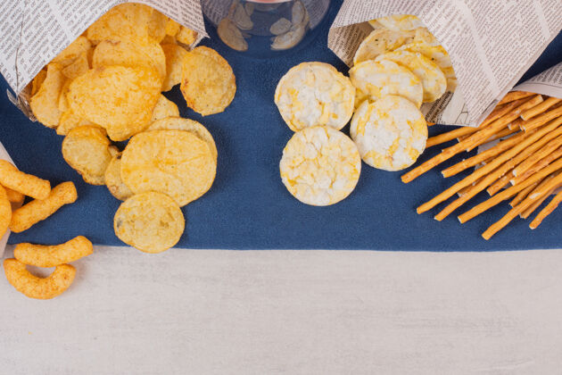 咸的薯片 饼干和椒盐脆饼放在蓝色桌布上小吃饼干顶视图