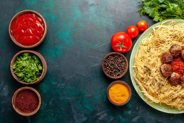 肉在深蓝色的桌子上俯瞰美味的意大利面食 里面有肉丸子和不同的调味品晚餐面团调味品