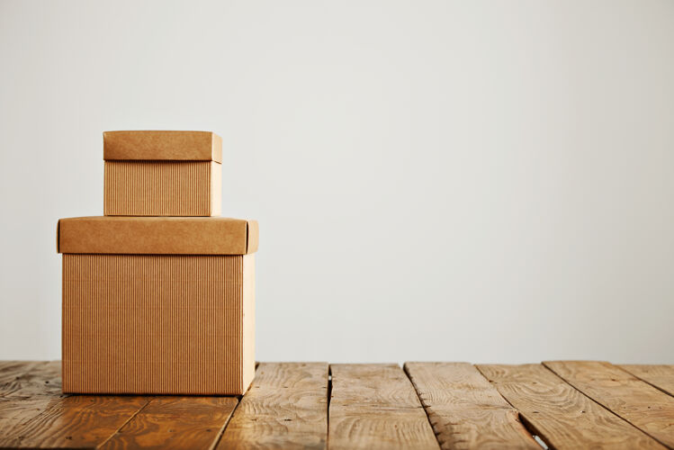 储存两个不同大小的米色瓦楞纸板未贴标签的盒子呈现在彼此的顶部 在白色上相互隔离盒子运输礼品
