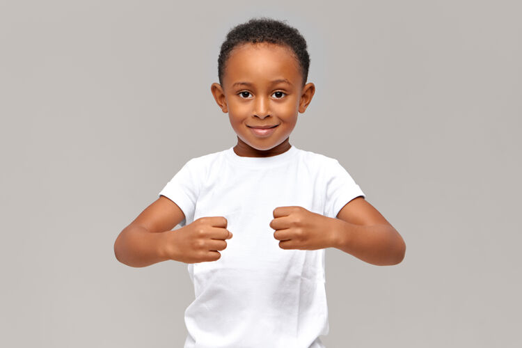 随意有趣的10岁非洲男孩穿着白色t恤 握紧拳头 展示力量或拿着看不见的东西非洲肖像童年