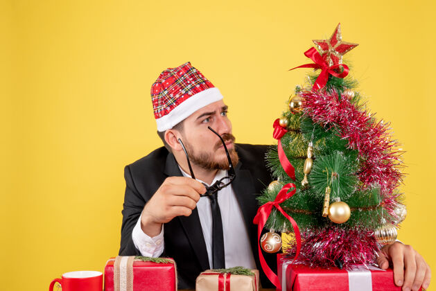 男正面图男性工人坐在他工作的地方后面 黄色的礼物工作圣诞节微笑