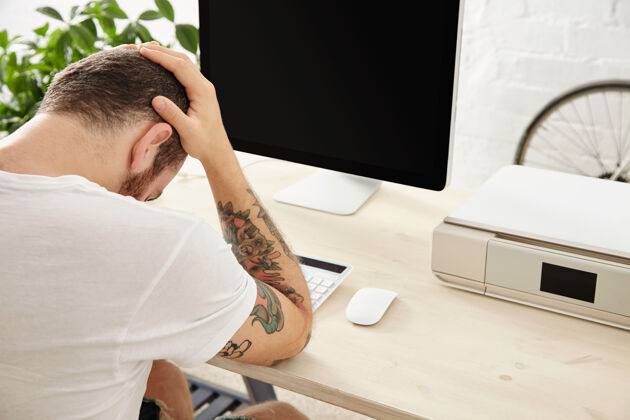 休闲悲伤的自由职业者有一个艰难的项目 并举行他的头在手 而坐在他的工作电脑屏幕前的侧视图工作在线年轻