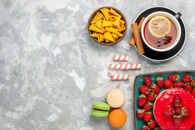 糖果顶视图美味的草莓蛋糕与新鲜的红色草莓一杯茶和麦卡龙在白色的背景草莓健康草莓