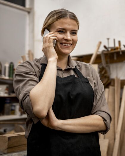 工作微笑女木匠在工作中使用智能手机劳动者贸易技能