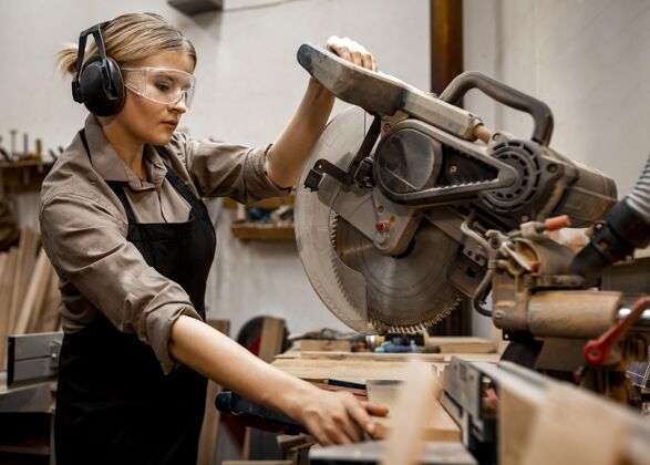 贸易女木匠在工作室里用电锯劳动者专业知识木匠