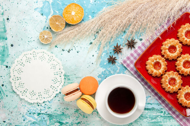 饼干上图：红色盘子里的糖饼干 蓝色背景上有一杯茶和麦卡龙画笔茶背景