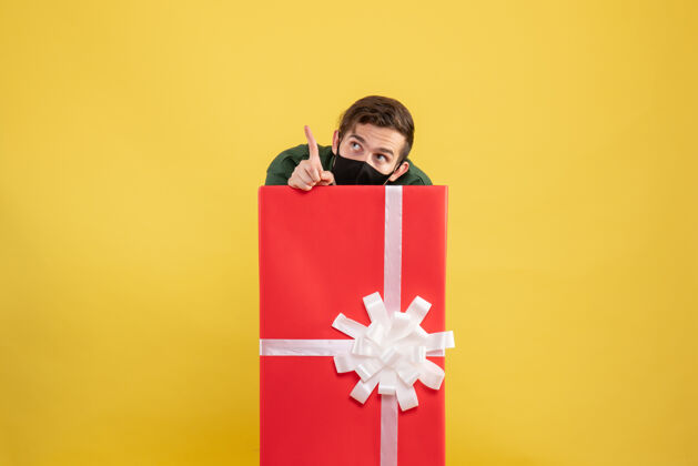 包正面图：年轻人躲在黄色的大礼品盒后面漂亮微笑礼物