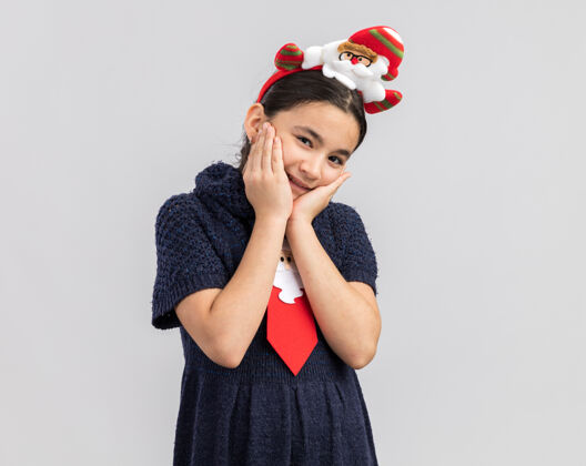 轮辋小女孩穿着针织连衣裙 头上系着一条红色领带 上面戴着有趣的圣诞戒指 看上去快乐而积极的微笑小新的年