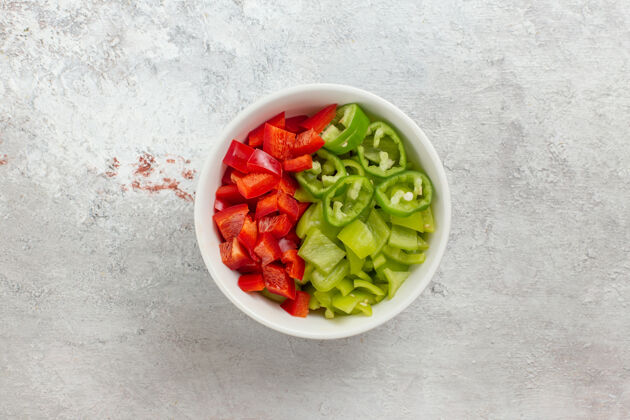 午餐顶视图切碎的甜椒辣味沙拉在白色背景的盘子里切片胡椒番茄