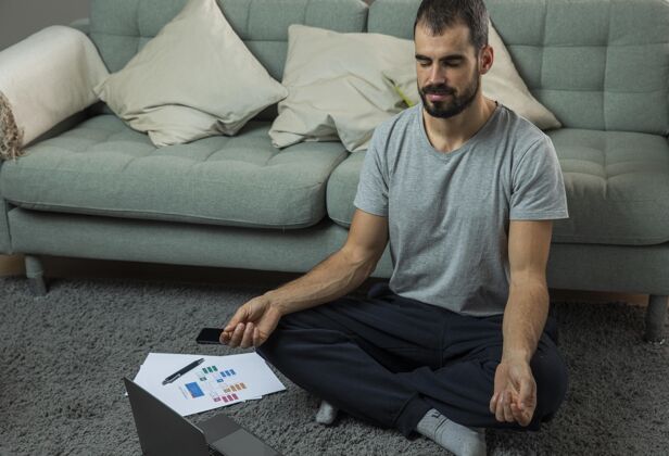 冥想开始工作前坐在沙发边冥想的男人职业笔记本电脑禅宗