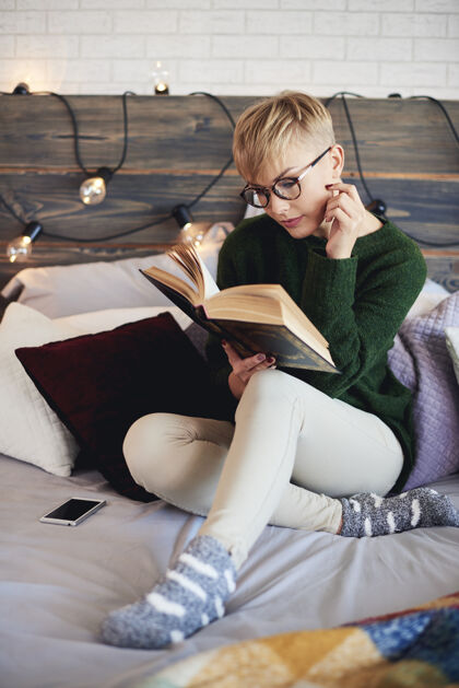 寒冷漂亮女孩在床上看书舒适书房毛衣